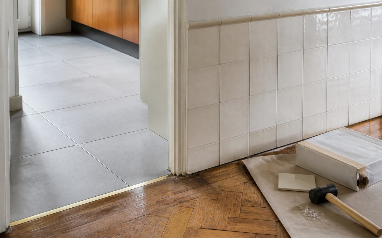 Encontro entre pavimento cerâmico, parquet recuperado e revestimento de parede